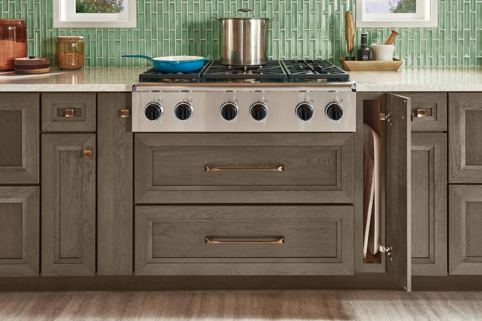 Design ideas for a mid-sized country kitchen in Detroit with recessed-panel cabinets, dark wood cabinets, quartz benchtops, green splashback, glass sheet splashback, stainless steel appliances, brown floor and white benchtop.