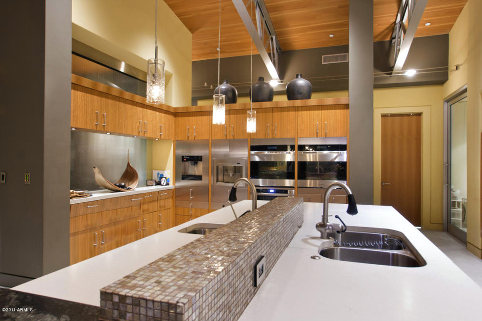 This is an example of an expansive modern l-shaped eat-in kitchen in Phoenix with an undermount sink, flat-panel cabinets, medium wood cabinets, concrete benchtops, multi-coloured splashback, glass tile splashback, stainless steel appliances, porcelain floors and multiple islands.