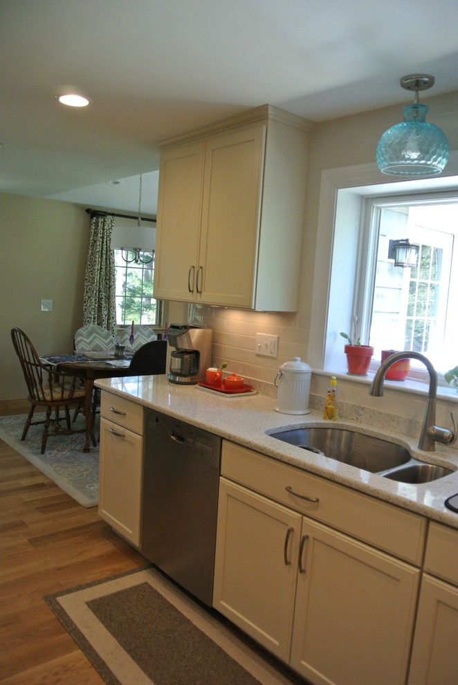 Inspiration for a transitional l-shaped medium tone wood floor eat-in kitchen remodel in Boston with an undermount sink, shaker cabinets, white cabinets, recycled glass countertops, white backsplash, subway tile backsplash, stainless steel appliances, a peninsula and white countertops
