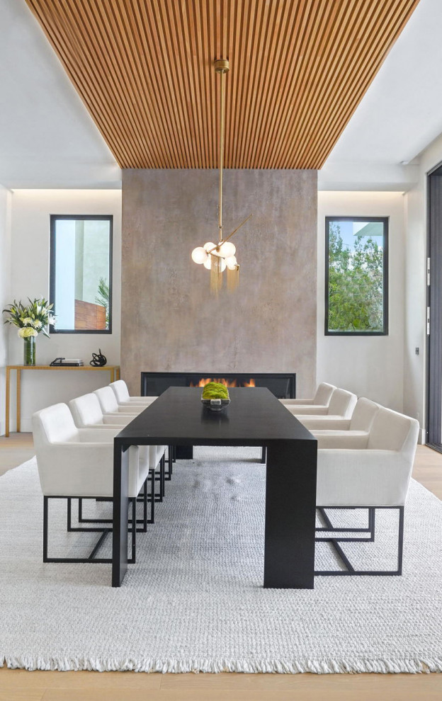 Идея дизайна: огромная кухня-столовая в современном стиле с белыми стенами, светлым паркетным полом, стандартным камином, фасадом камина из штукатурки, коричневым полом и деревянным потолком