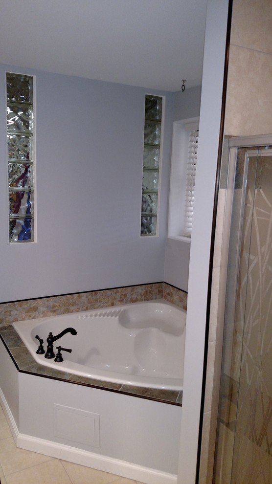 Example of a mid-sized transitional master porcelain tile and beige floor corner bathtub design with shaker cabinets, black cabinets, a two-piece toilet, gray walls, an undermount sink, laminate countertops, a hinged shower door and beige countertops