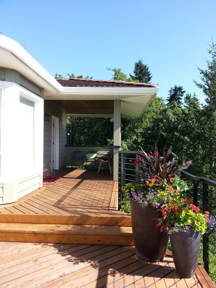 This is an example of a contemporary deck in Portland with a roof extension.