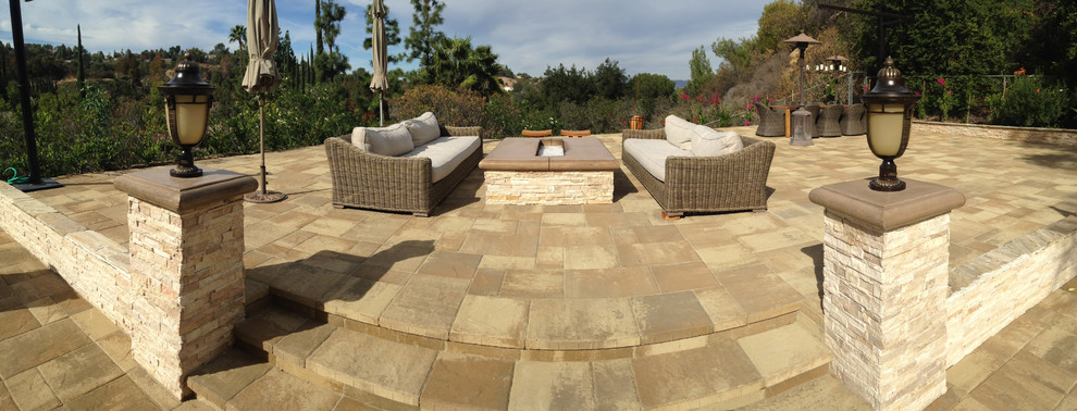 Large modern backyard patio in Los Angeles with a fire feature, natural stone pavers and no cover.