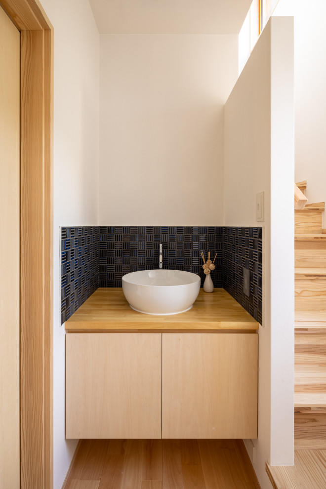 Esempio di un bagno di servizio moderno con piastrelle blu, piastrelle in gres porcellanato, pavimento in legno massello medio, lavabo da incasso, mobile bagno incassato e soffitto in carta da parati