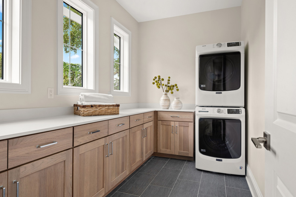 Inspiration for a large beach style laundry room in Orlando with shaker cabinets, light wood cabinets, marble benchtops, white walls, porcelain floors, a stacked washer and dryer and white benchtop.