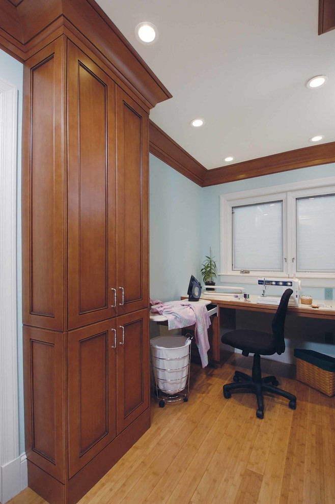Inspiration for a traditional u-shaped laundry room in San Francisco with medium wood cabinets, laminate benchtops, blue walls, bamboo floors and a concealed washer and dryer.