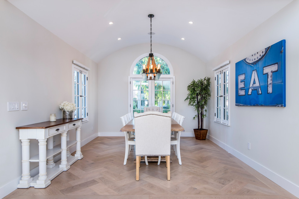 This is an example of a large traditional separate dining room in Los Angeles with beige walls, light hardwood floors, no fireplace, brown floor and vaulted.
