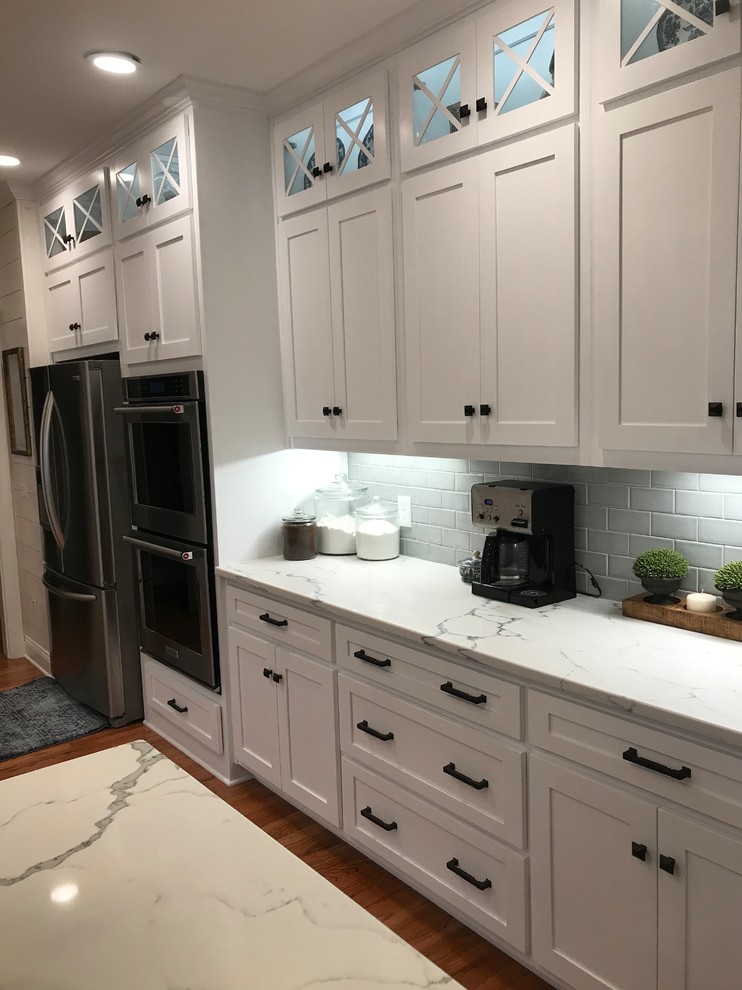 Eat-in kitchen - mid-sized transitional u-shaped medium tone wood floor and brown floor eat-in kitchen idea in Atlanta with a farmhouse sink, shaker cabinets, white cabinets, subway tile backsplash, stainless steel appliances, an island and granite countertops