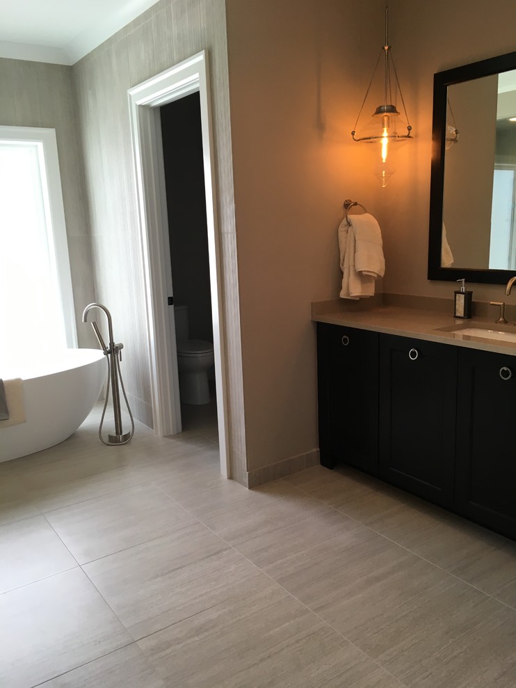 Example of a large transitional master beige tile and porcelain tile porcelain tile and beige floor freestanding bathtub design in Chicago with shaker cabinets, dark wood cabinets, a two-piece toilet, brown walls, an undermount sink, quartz countertops, a hinged shower door and beige countertops