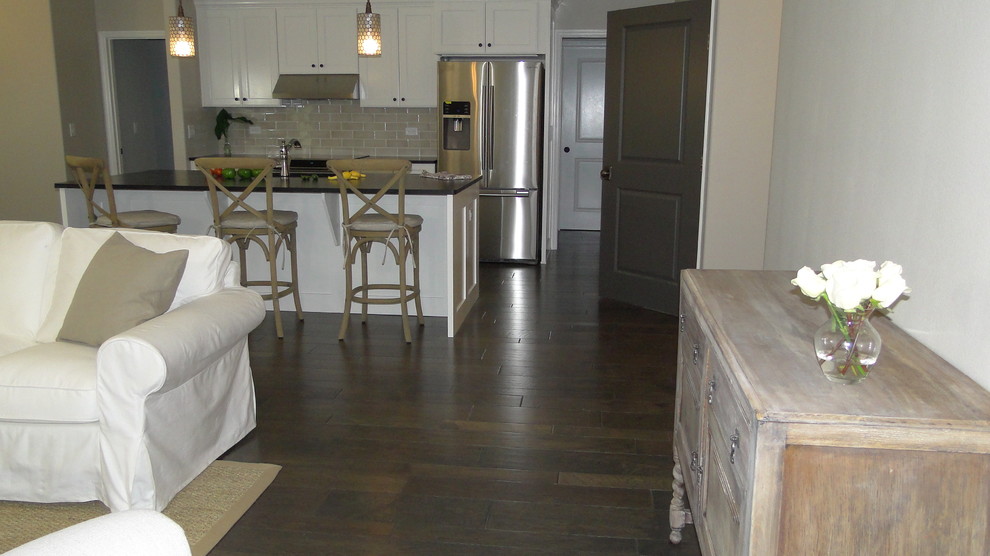 Kitchen - transitional medium tone wood floor kitchen idea in Jacksonville with white cabinets, beige backsplash, subway tile backsplash, stainless steel appliances and an island