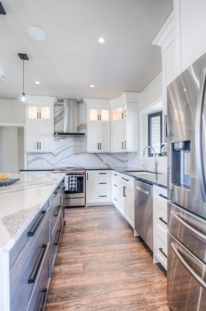 Example of a transitional eat-in kitchen design with shaker cabinets, white cabinets, stainless steel appliances and an island