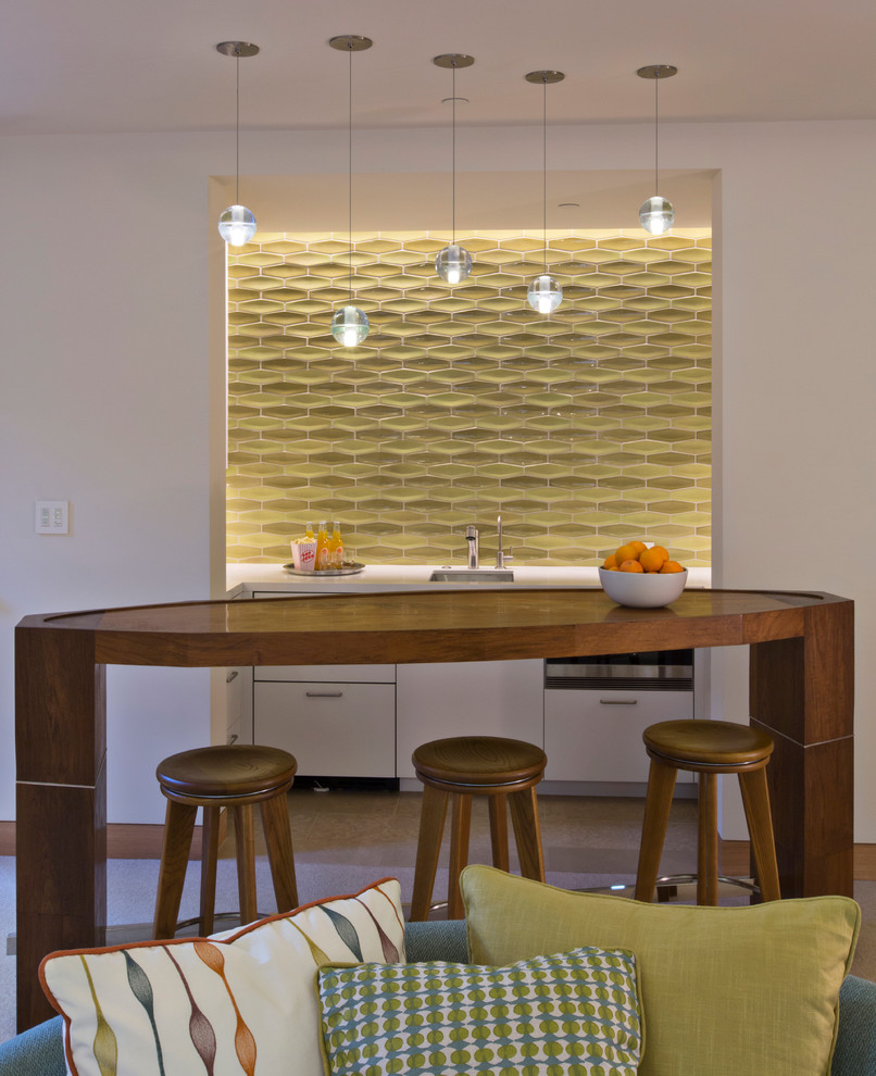 This is an example of a mid-sized contemporary seated home bar in San Francisco with an undermount sink, flat-panel cabinets, white cabinets, green splashback, quartz benchtops, ceramic splashback, ceramic floors and white benchtop.