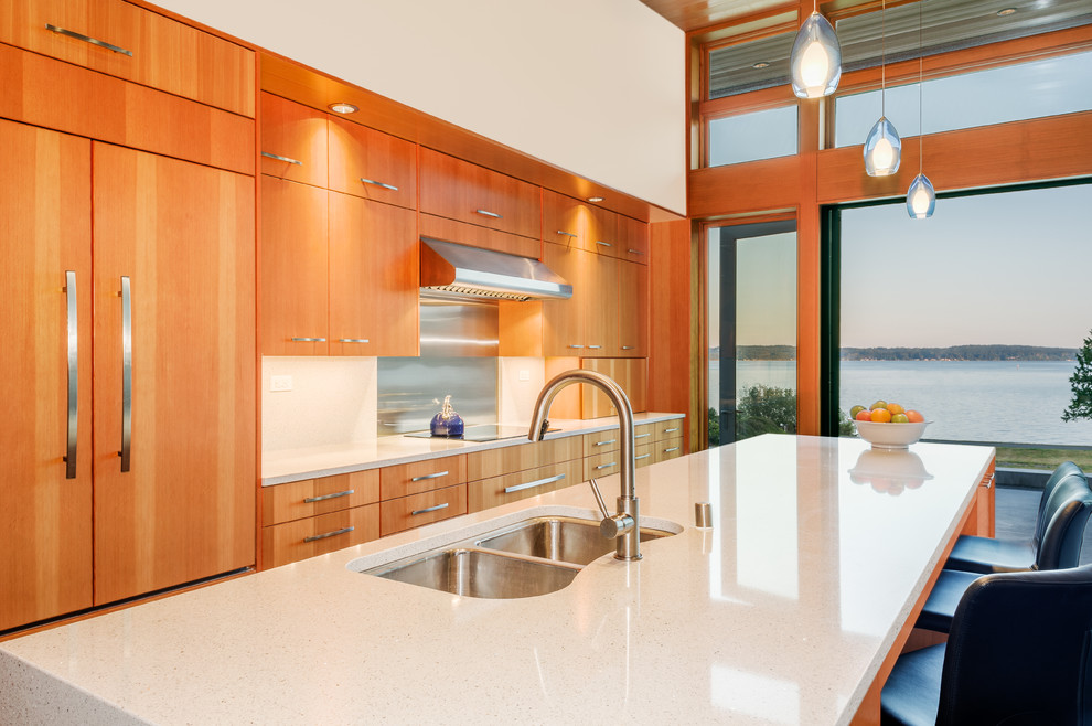 Inspiration for a small contemporary single-wall open plan kitchen in Seattle with a double-bowl sink, flat-panel cabinets, medium wood cabinets, quartz benchtops, white splashback, glass sheet splashback, stainless steel appliances, with island and concrete floors.