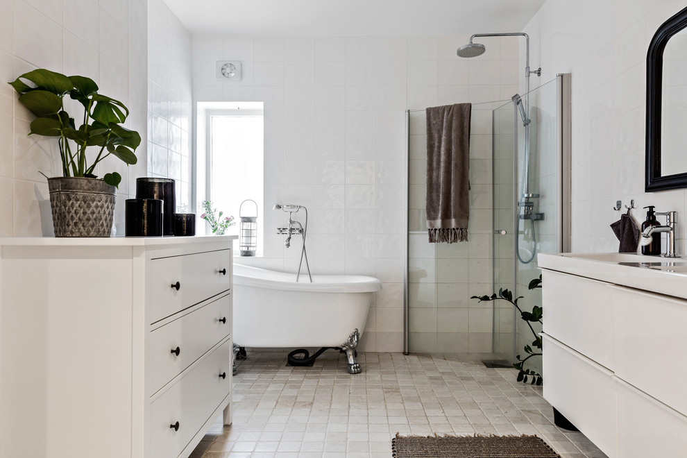 Photo of a scandinavian master bathroom in Gothenburg with flat-panel cabinets, white cabinets, a claw-foot tub, a corner shower, white tile, white walls, beige floor and a hinged shower door.