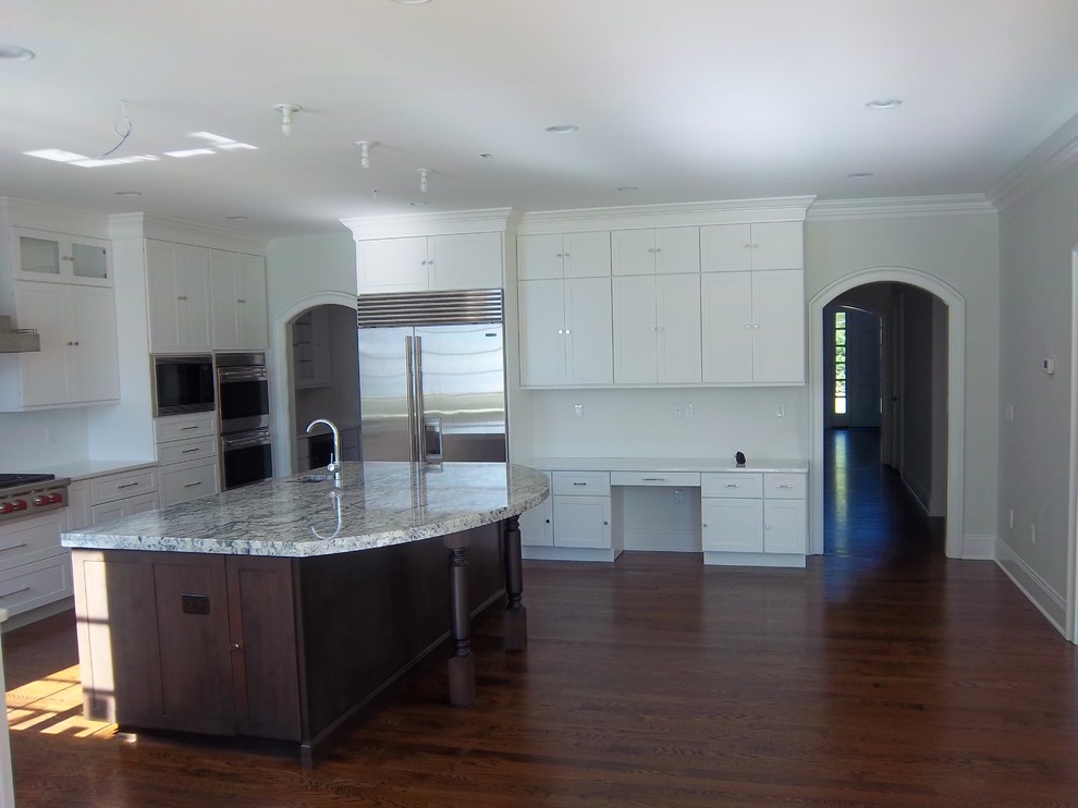 Inspiration for a large transitional u-shaped dark wood floor and brown floor eat-in kitchen remodel with shaker cabinets, white cabinets, white backsplash, stainless steel appliances, an island, an undermount sink, solid surface countertops and white countertops