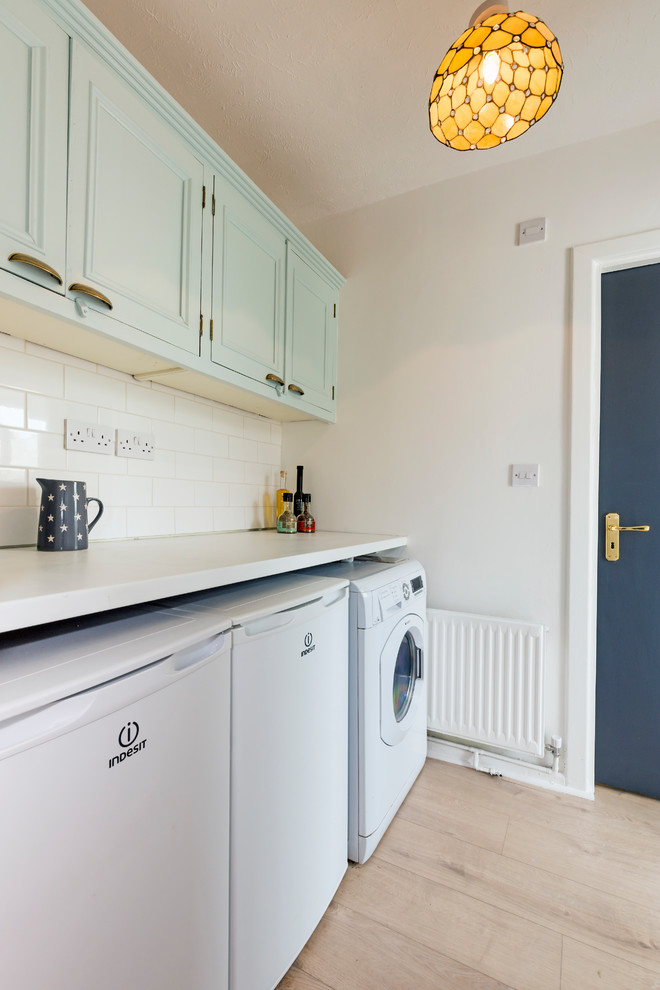 This is an example of a small traditional single-wall laundry cupboard in Dublin with an undermount sink, turquoise cabinets, wood benchtops, white walls, laminate floors, a side-by-side washer and dryer, grey floor and white benchtop.