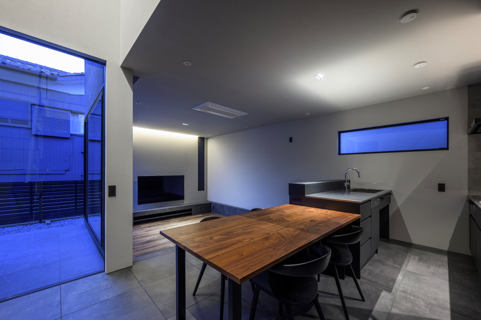 Mid-sized contemporary galley eat-in kitchen in Other with an integrated sink, flat-panel cabinets, grey cabinets, stainless steel benchtops, grey splashback, ceramic splashback, black appliances, ceramic floors, with island, grey floor, black benchtop and wallpaper.