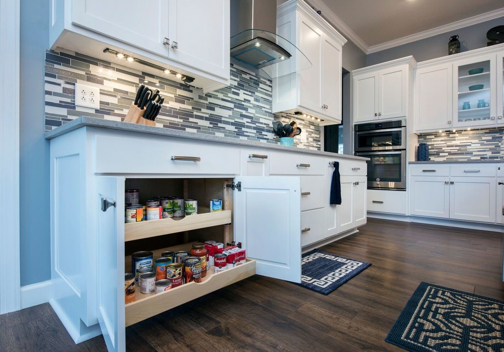 Enclosed kitchen - mid-sized transitional single-wall dark wood floor and brown floor enclosed kitchen idea in Columbus with a farmhouse sink, shaker cabinets, white cabinets, granite countertops, multicolored backsplash, matchstick tile backsplash, stainless steel appliances, an island and gray countertops