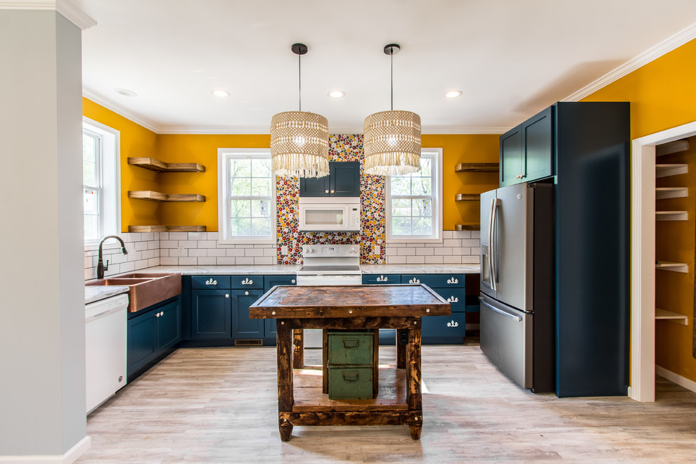 This is an example of a mid-sized traditional l-shaped eat-in kitchen in Other with a farmhouse sink, flat-panel cabinets, blue cabinets, laminate benchtops, white splashback, ceramic splashback, white appliances, laminate floors, with island, grey floor and white benchtop.