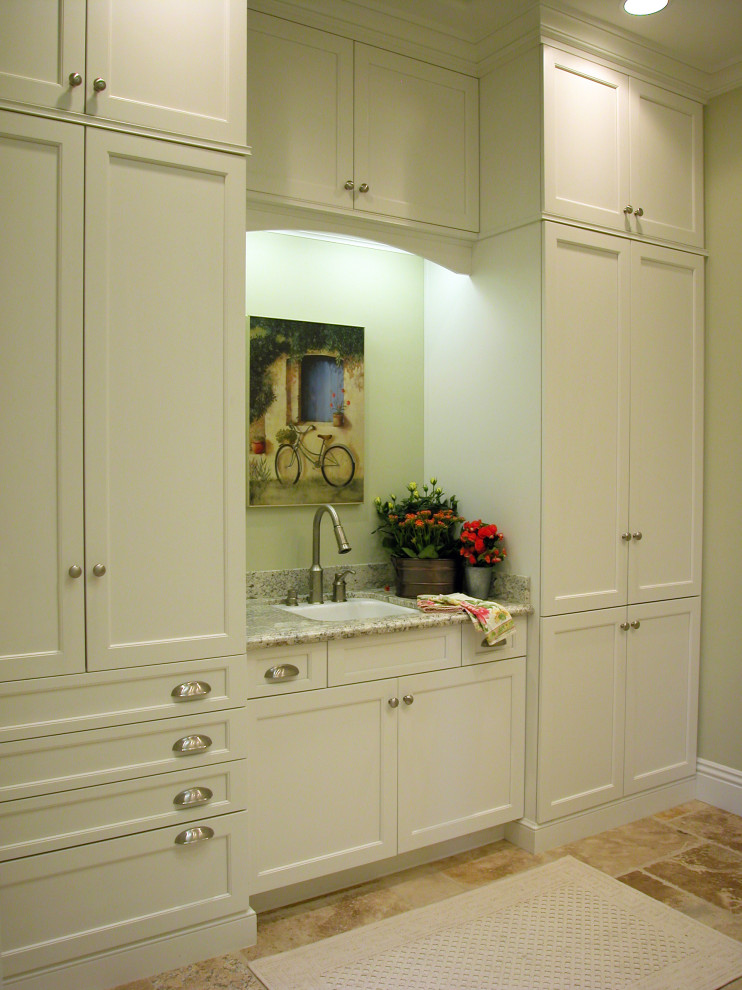Foto di una grande sala lavanderia tradizionale con lavello sottopiano, ante in stile shaker, ante bianche, top in granito, pavimento in travertino e top bianco