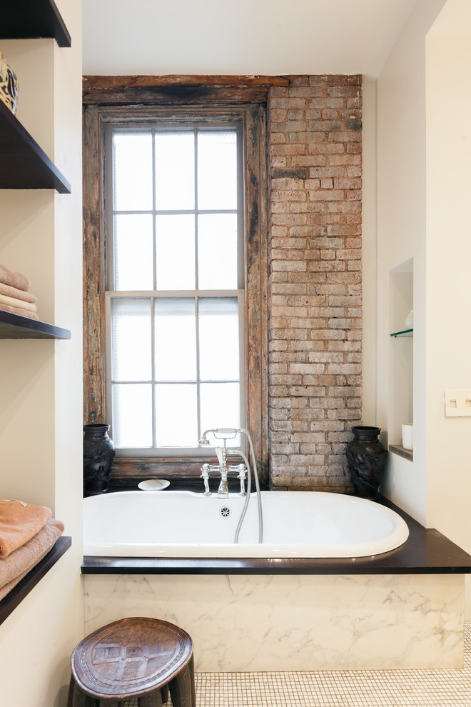 Design ideas for an industrial master bathroom in New York with open cabinets, a drop-in tub and white walls.