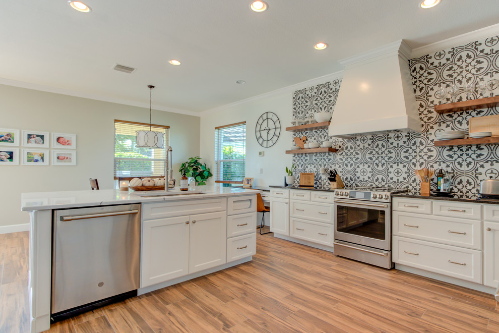 Eat-in kitchen - large transitional l-shaped ceramic tile and brown floor eat-in kitchen idea with an undermount sink, shaker cabinets, white cabinets, quartz countertops, multicolored backsplash, ceramic backsplash, stainless steel appliances, an island and white countertops