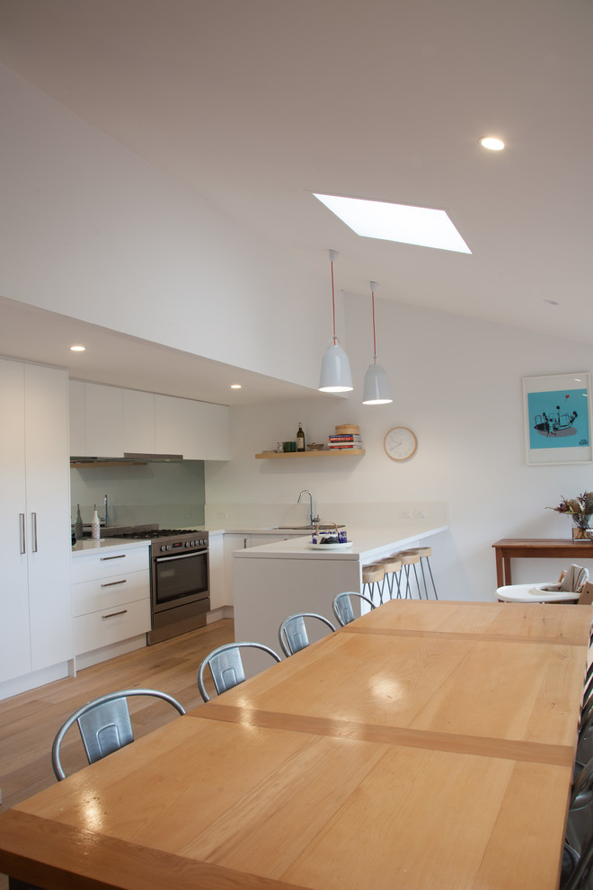 This is an example of a large contemporary kitchen/dining combo in Sydney with white walls and light hardwood floors.