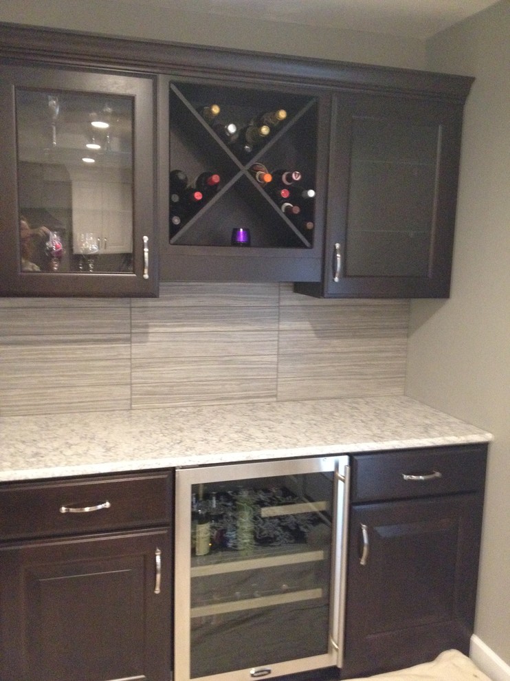Inspiration for a mid-sized transitional single-wall dark wood floor home design remodel in Chicago with raised-panel cabinets, granite countertops, gray backsplash, ceramic backsplash, stainless steel appliances, an island, no sink and brown cabinets