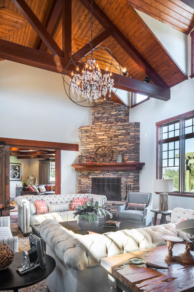 Design ideas for an expansive eclectic formal open concept living room in Santa Barbara with medium hardwood floors, a corner fireplace, a stone fireplace surround and grey walls.