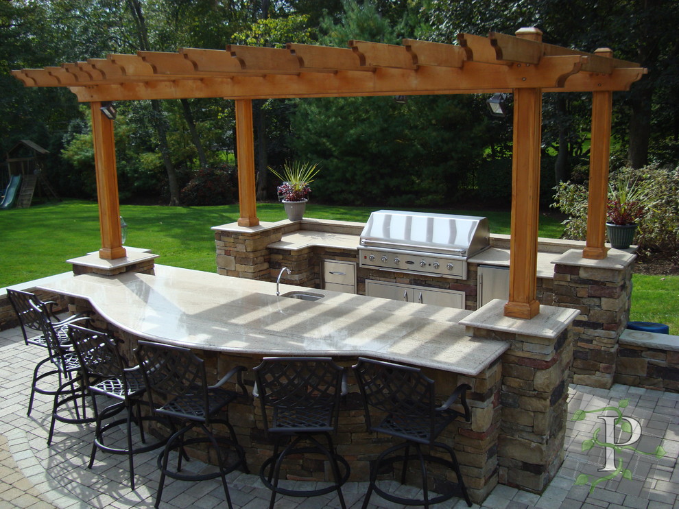 Design ideas for a mid-sized traditional backyard patio in New York with an outdoor kitchen, natural stone pavers and a pergola.