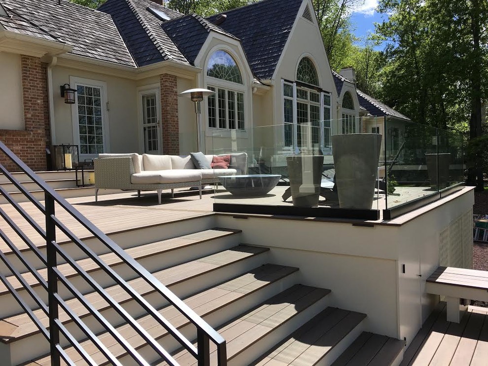 This is an example of an expansive contemporary backyard deck in Philadelphia with a pergola.