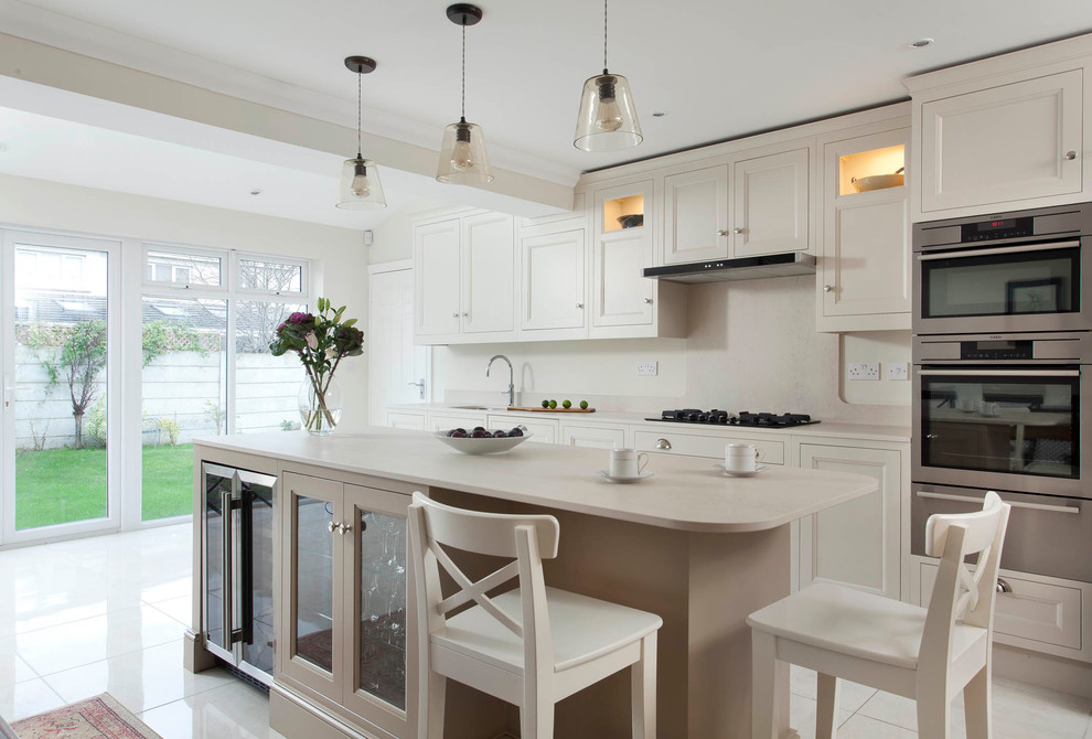 Design ideas for a large transitional single-wall open plan kitchen in Dublin with an undermount sink, beaded inset cabinets, beige cabinets, quartzite benchtops, beige splashback, stone slab splashback, stainless steel appliances, porcelain floors and with island.