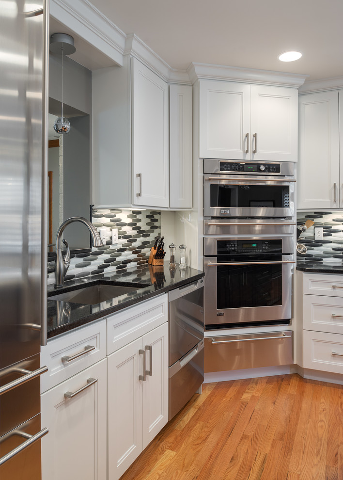 Inspiration for a transitional l-shaped light wood floor eat-in kitchen remodel in St Louis with an undermount sink, shaker cabinets, white cabinets, quartz countertops, metallic backsplash, glass tile backsplash, stainless steel appliances and an island