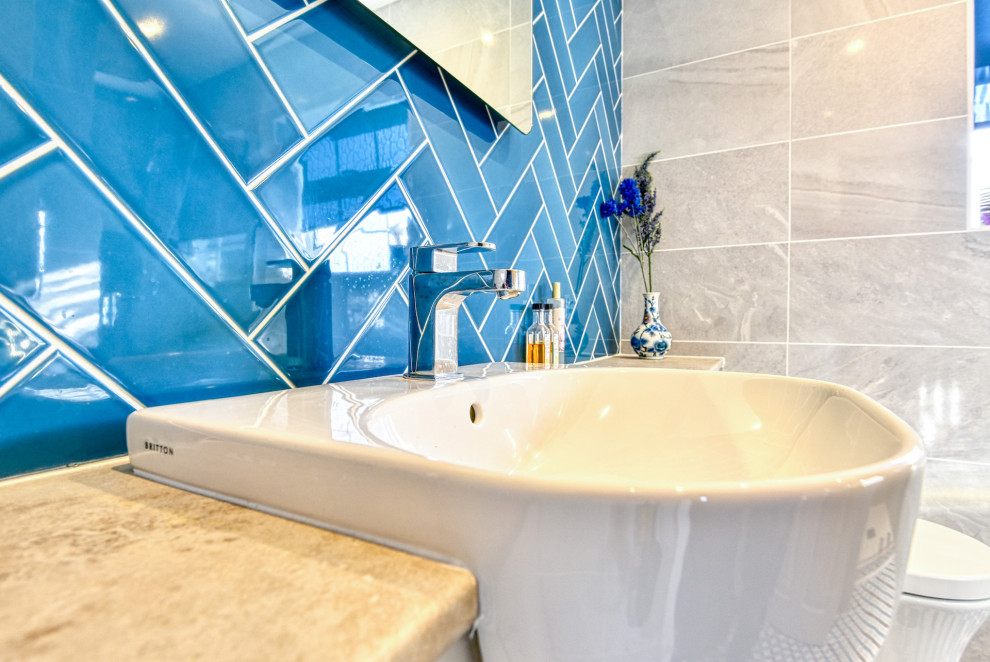 サセックスにあるお手頃価格の中くらいなモダンスタイルのおしゃれなバスルーム (浴槽なし) (フラットパネル扉のキャビネット、ベージュのキャビネット、アルコーブ型シャワー、壁掛け式トイレ、青いタイル、サブウェイタイル、ベージュの壁、セラミックタイルの床、コンソール型シンク、ラミネートカウンター、マルチカラーの床、開き戸のシャワー、ベージュのカウンター、照明、洗面台1つ、造り付け洗面台、グレーとクリーム色) の写真