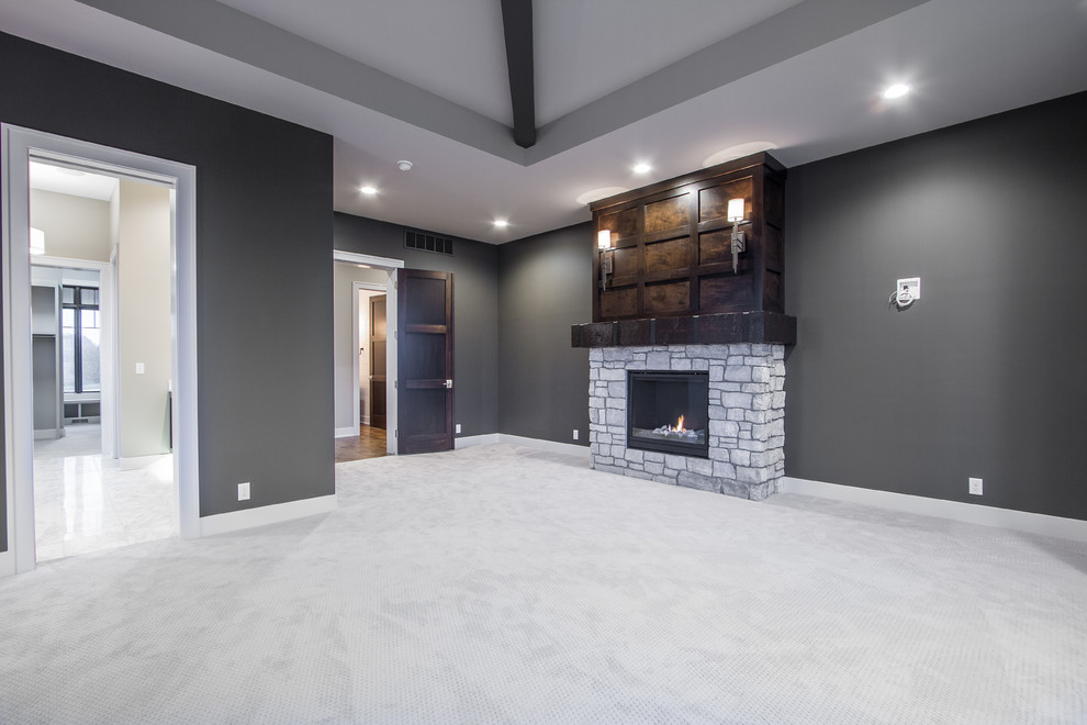 Design ideas for a large transitional master bedroom in Omaha with grey walls, carpet, a hanging fireplace and a stone fireplace surround.