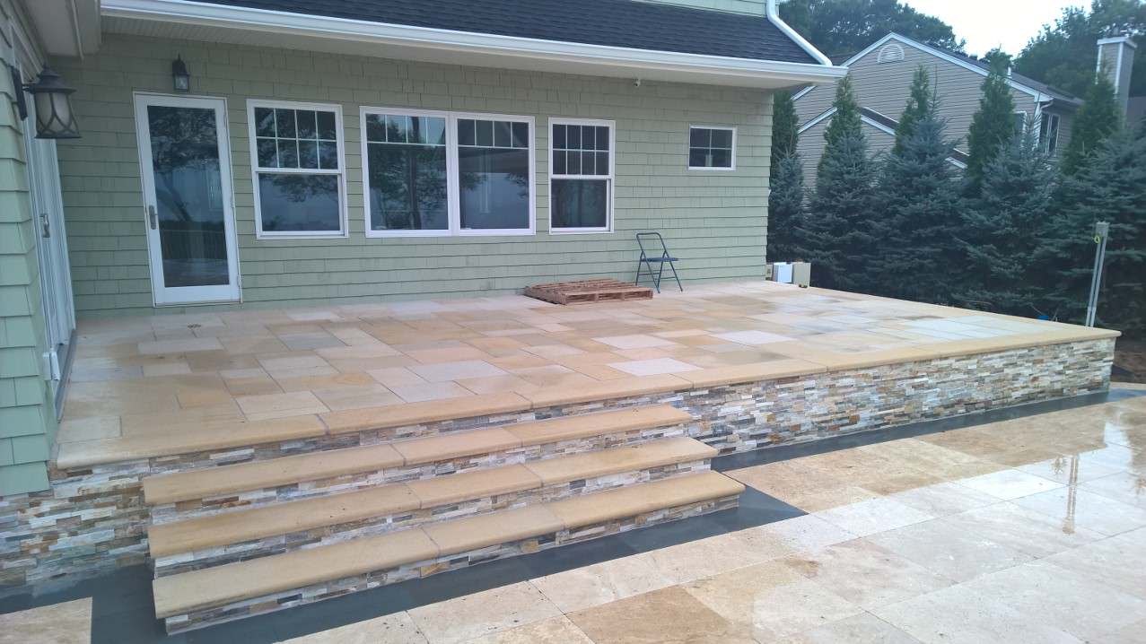 Raised patio using a natural tan stone with veneer on the face