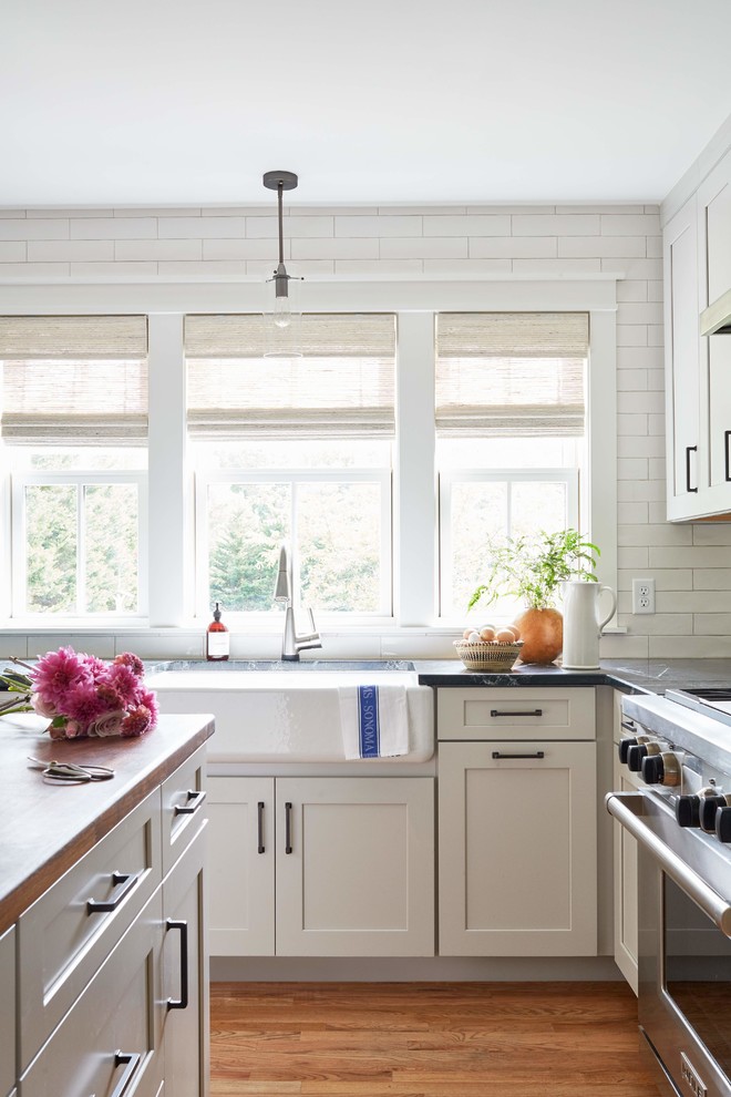 Rockville - Inspiration for a large cottage l-shaped medium tone wood floor and brown floor enclosed kitchen remodel in Richmond with a farmhouse sink, shaker cabinets, gray cabinets, soapstone countertops, white backsplash, subway tile backsplash, stainless steel appliances, an island and black countertops