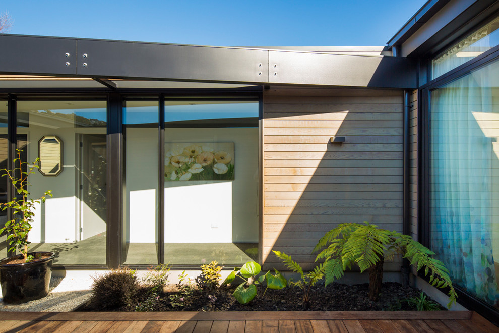 Contemporary courtyard patio in Christchurch with decking and a pergola.