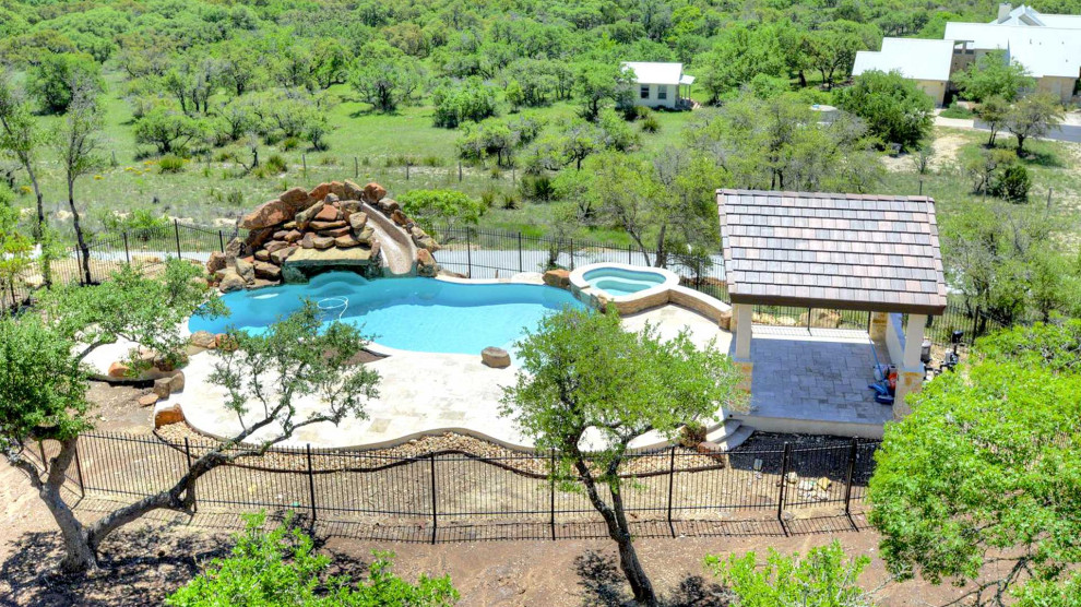 Design ideas for a large traditional backyard custom-shaped pool in Austin with a water feature and decking.