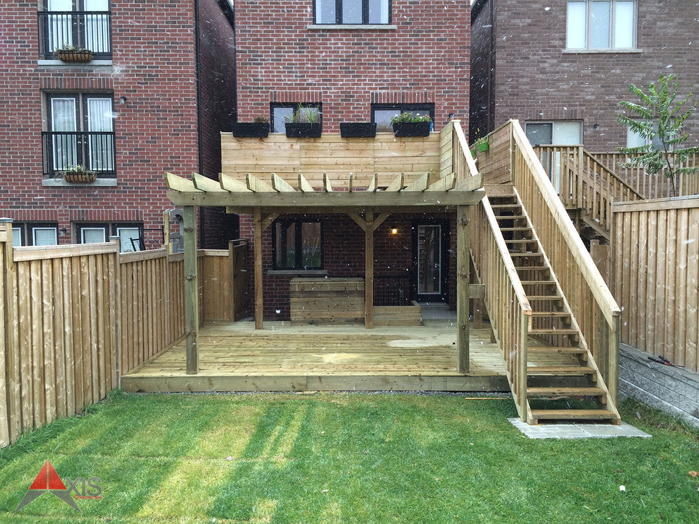 This is an example of an expansive modern backyard deck in Toronto with a pergola.