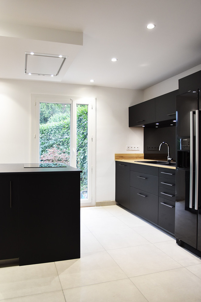 Mid-sized modern galley separate kitchen in Lyon with laminate benchtops, black appliances, ceramic floors, with island, beige floor, beaded inset cabinets, black cabinets, black splashback, glass sheet splashback and a double-bowl sink.