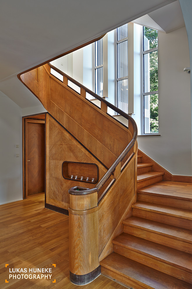 Photo of an expansive contemporary wood u-shaped staircase in Other with wood risers.