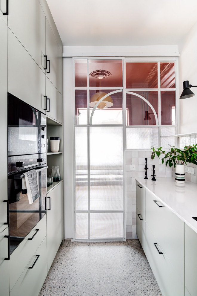 Idéer för att renovera ett avskilt, mellanstort funkis vit vitt l-kök, med en undermonterad diskho, släta luckor, gröna skåp, bänkskiva i kvarts, vitt stänkskydd, svarta vitvaror, terrazzogolv och vitt golv