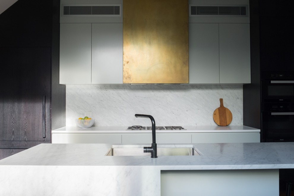Design ideas for a large contemporary galley kitchen in Sydney with an undermount sink, flat-panel cabinets, white cabinets, marble benchtops, marble splashback, black appliances and with island.
