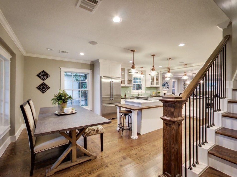Mid-sized transitional l-shaped medium tone wood floor and brown floor eat-in kitchen photo with an undermount sink, glass-front cabinets, white cabinets, solid surface countertops, green backsplash, subway tile backsplash, stainless steel appliances and an island