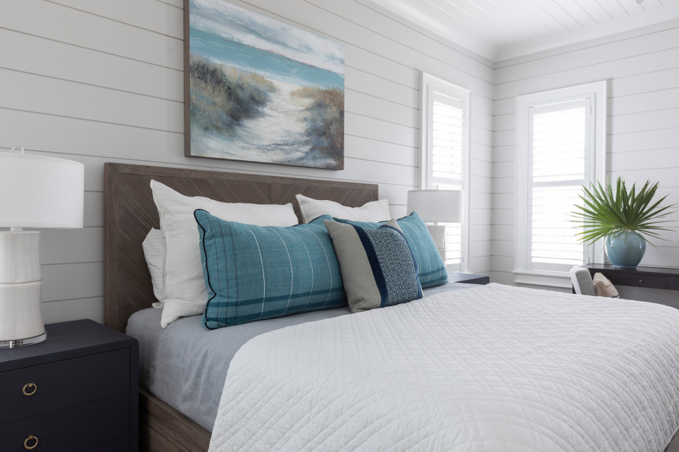 Large beach style master bedroom in Other with white walls, light hardwood floors, brown floor, timber and planked wall panelling.