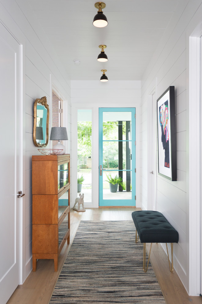 Photo of a mid-sized transitional entry hall in Austin with white walls, light hardwood floors, a single front door and a blue front door.