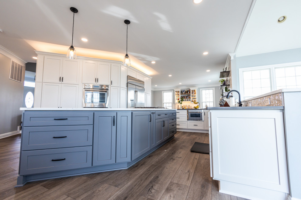Kitchen - large transitional vinyl floor and brown floor kitchen idea in Baltimore with an undermount sink, shaker cabinets, white backsplash, porcelain backsplash, stainless steel appliances, an island and white countertops