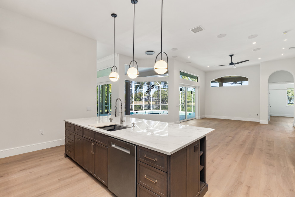 Eat-in kitchen - large transitional galley light wood floor and brown floor eat-in kitchen idea in Tampa with a double-bowl sink, shaker cabinets, dark wood cabinets, quartz countertops, gray backsplash, stone slab backsplash, stainless steel appliances, an island and gray countertops