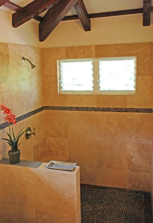 This is an example of a mid-sized beach style master bathroom in Hawaii with an open shower, a two-piece toilet, pebble tile, yellow walls, an undermount sink, shaker cabinets, light wood cabinets, limestone benchtops and travertine floors.
